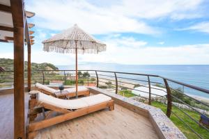 a balcony with chairs and an umbrella and the ocean at Aegean Balcony Apartment in Nea Peramos