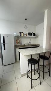 a kitchen with two chairs and a counter with a refrigerator at Apartamento da Rosa Rua Epaminondas Otoni Número 777 in Teófilo Otoni