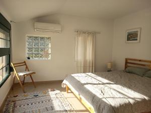 a white bedroom with a bed and a window at La Llar del Magraner in Barraca de Aguas Vivas +82 photos