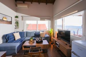 a living room with a blue couch and a tv at Aegean Balcony Apartment in Nea Peramos