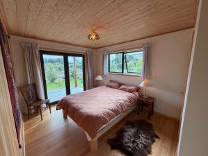 a bedroom with a bed and a large window at Whare Aorere in Collingwood