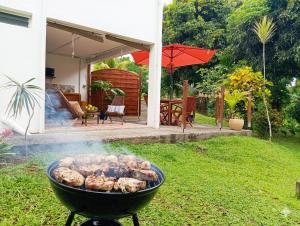 a barbecue grill in a yard next to a house at Studio Anthurium in Gros-Morne