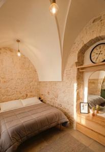 a bedroom with a bed and a clock on the wall at Almurigini I Boutique House I Ceglie Messapica in Ceglie Messapica