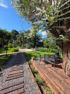 a wooden deck with two benches and a tree at Los robles in San Pedro