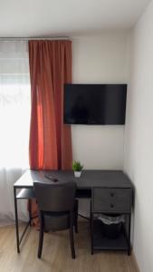 a desk with a chair and a television on a wall at Hotel Alden in Aldenhoven