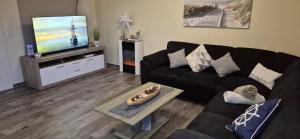 a living room with a black couch and a flat screen tv at Ferienhaus Seeschwalbe in Fehmarn
