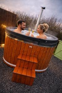 a man and woman in a hot tub with glasses of champagne at Grass Roots Retreat in Llanstadwell