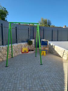 a swing set in a backyard with a fence at Casa Oliveira in Silves