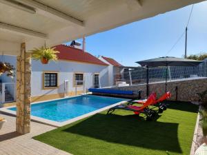 a swimming pool with an umbrella and a red chair at Casa Oliveira in Silves