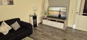 a living room with a couch and a flat screen tv at Ferienhaus Seeschwalbe in Fehmarn +17 photos
