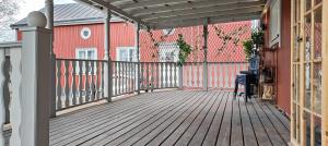 a wooden deck with a red house and a fence at Nordic DeLight in Skelleftehamn