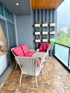 a balcony with two wicker chairs and a table with pink pillows at Premium Murree Apartment With Stunning Views in Murree +7 photos