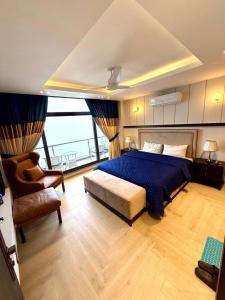 a bedroom with a bed and a chair and a window at Premium Murree Apartment With Stunning Views in Murree