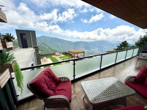 a balcony with two chairs and a table and mountains at Premium Murree Apartment With Stunning Views in Murree