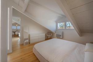 a white bedroom with a bed and a staircase at Attico Mansardato con terrazzo privato in Monza