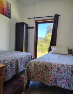 a bedroom with two beds and a window at Cabaña la nonita, queule in Queule
