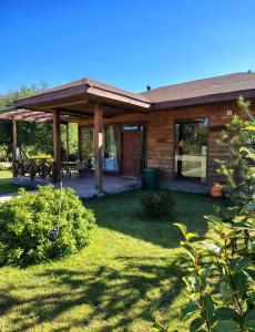 a wooden house with a porch and a patio at Cabaña la nonita, queule in Queule