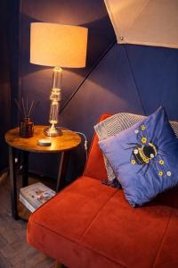 a room with a red chair and a table with a lamp at Alpaca Hideaway in Llanstadwell