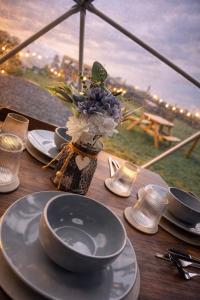 a wooden table with plates and a vase of flowers at Alpaca Hideaway in Llanstadwell