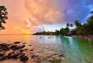 a beach with a group of people in the water at VILLA Ti-COULANGE, Verdoyante in Rivière-Pilote