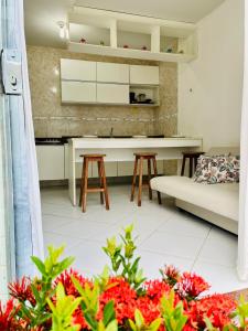 eine Küche und ein Wohnzimmer mit Sofa und Tisch in der Unterkunft Flat Granito e Jasmim in Conde