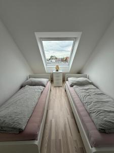 two beds in a room with a window at Leo Stay in Leopoldsdorf