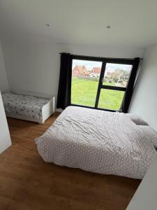 a bedroom with a bed and a large window at Saint Pierre Gîte in Ambleteuse