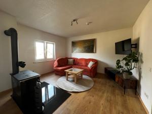 a living room with a red couch and a table at Hofquartier in ruhiger Lage Eisenach & Hainich in Beuernfeld