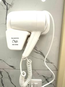 a white hairdryer hanging on a wall at Taku Rooms Vlora in Vlorë