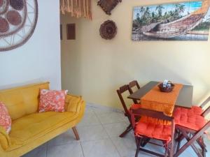 a dining room with a table and a yellow couch at Rancho Magic in Cabo Frio