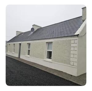 a white building with a black roof at Chambers Cottage in Drumellihy