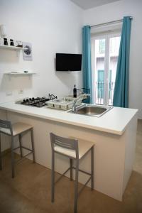 a kitchen with a sink and a counter with stools at Kalsa’s House Noto in Noto
