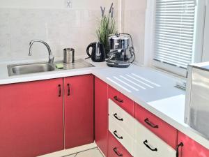 a kitchen with red cabinets and a sink at Apartament Bursztynowy in Ustka +3 photos