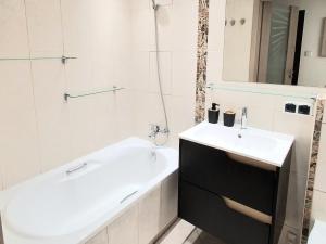 a bathroom with a sink and a bath tub and a sink at Apartament Bursztynowy in Ustka