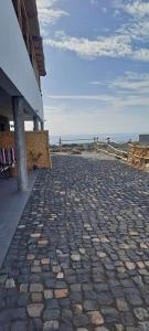 a stone walkway next to a building next to the beach at Kasa surf in Porto Novo +37 photos
