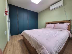 a bedroom with a large bed with pink pillows at 비우리게스트하우스 in Kujŏm