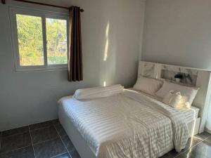 a white bed in a room with a window at Sunshine Rest Resort in Ubon Ratchathani