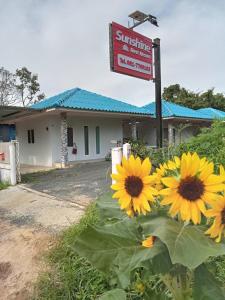 a sign in front of a building with yellow flowers at Sunshine Rest Resort in Ubon Ratchathani