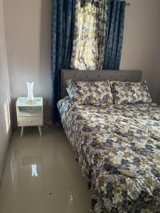 a bedroom with a bed and a night stand with a vase at Grace in Spanish Town