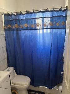 a blue shower curtain in a bathroom with a toilet at Grace in Spanish Town