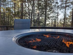 a fire pit on a patio with a chair and trees at Pinetop Getaway w Sunset Deck & Fire Pit Table in Pinetop-Lakeside