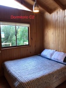 a bed in a wooden room with a window at Bahía Coliumo in Tomé