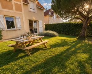 a wooden picnic table in the yard of a house at L Echappee Jardin prive proche plage Sainte Cecile in Camiers