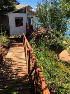 a wooden walkway leading to a house with a porch at Bahía Coliumo in Tomé +3 photos