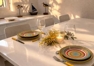 a white table with two plates and wine glasses at L Echappee Jardin prive proche plage Sainte Cecile in Camiers