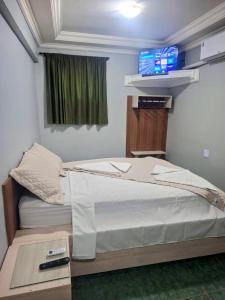 a bedroom with a bed with a tv on the wall at Arion Hotel Sapopemba in São Paulo