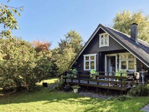 a black cottage with a porch and windows at 4 person holiday home in Odder in Odder +19 photos