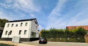 a car parked in front of a white building at Le Petit - Ihre Pension in Essen in Essen