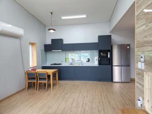 a large kitchen with a table and a refrigerator at 비우리게스트하우스 in Kujŏm