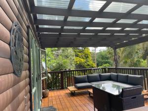a patio with a couch and a table on a deck at Fernside Tranquil Retreat in Pauanui